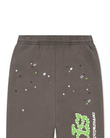 Sp5der P*nk V1 Sweatpants slate grey, close-up of the green, white and black star scatter above the leg logo