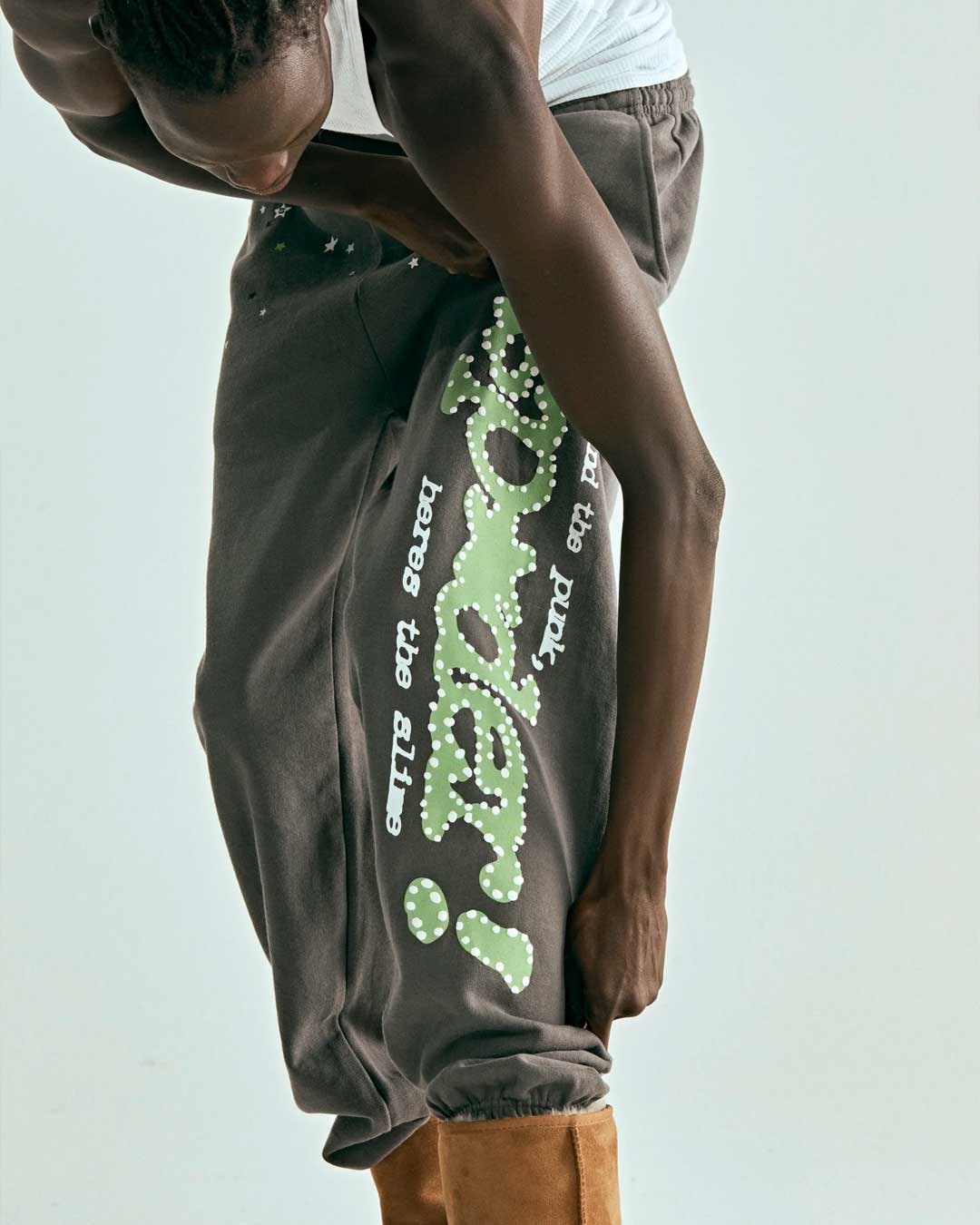 Sp5der P*nk V1 Sweatpants slate grey, worn on model, angled close-up of the leg graphic and star print