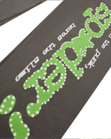 Sp5der P*nk V1 Sweatpants slate grey, angled close-up of the lime green dotted sp5der logo and white surrounding lettering