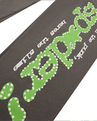 Sp5der P*nk V1 Sweatpants slate grey, angled close-up of the lime green dotted sp5der logo and white surrounding lettering
