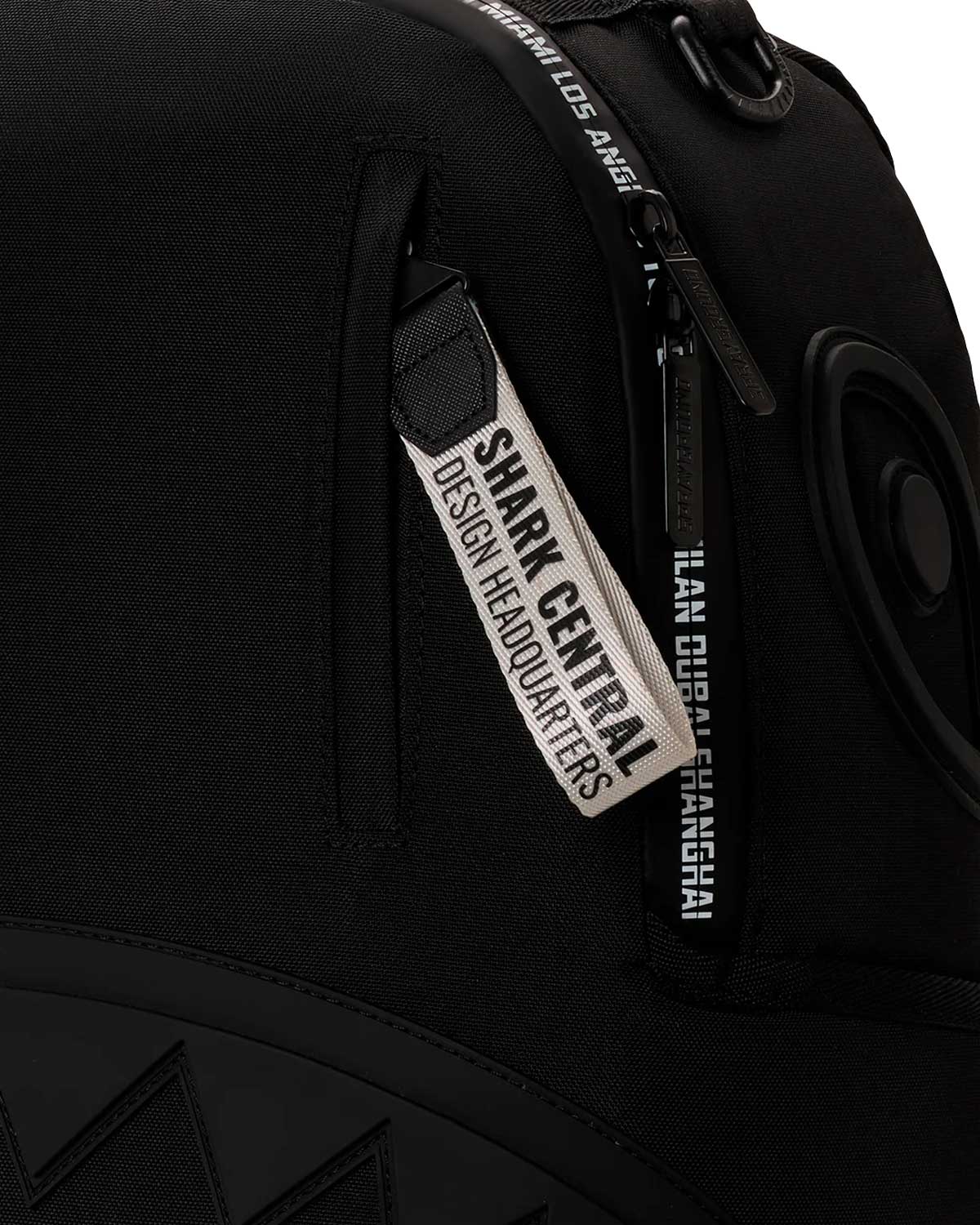Sprayground Shark Central Printed Zip Backpack, close-up of the Shark Central Design Headquarters pull tag