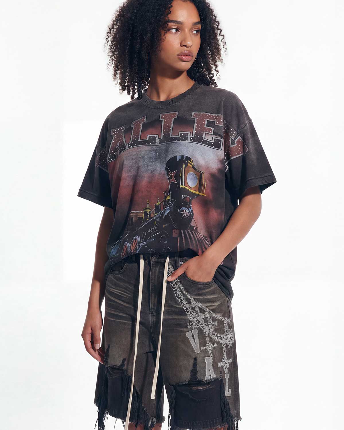 A model wearing a washed black graphic t-shirt with a vintage train illustration and the word 'ALLES' on the front, paired with distressed dark shorts, against a plain white background.