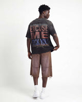 A man shown from the back wearing a dark gray graphic t-shirt with a distressed 'EXCUSE ME F*CK YOU!' print, brown frayed mid-calf shorts, white socks, and white sneakers, against a plain white studio background.