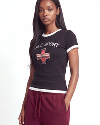 Vale Forever Emergency Femme Tee black, cropped on-body view of the distressed VALE SPORT lettering and red-and-white cross graphic with white ringer collar and cuffs
