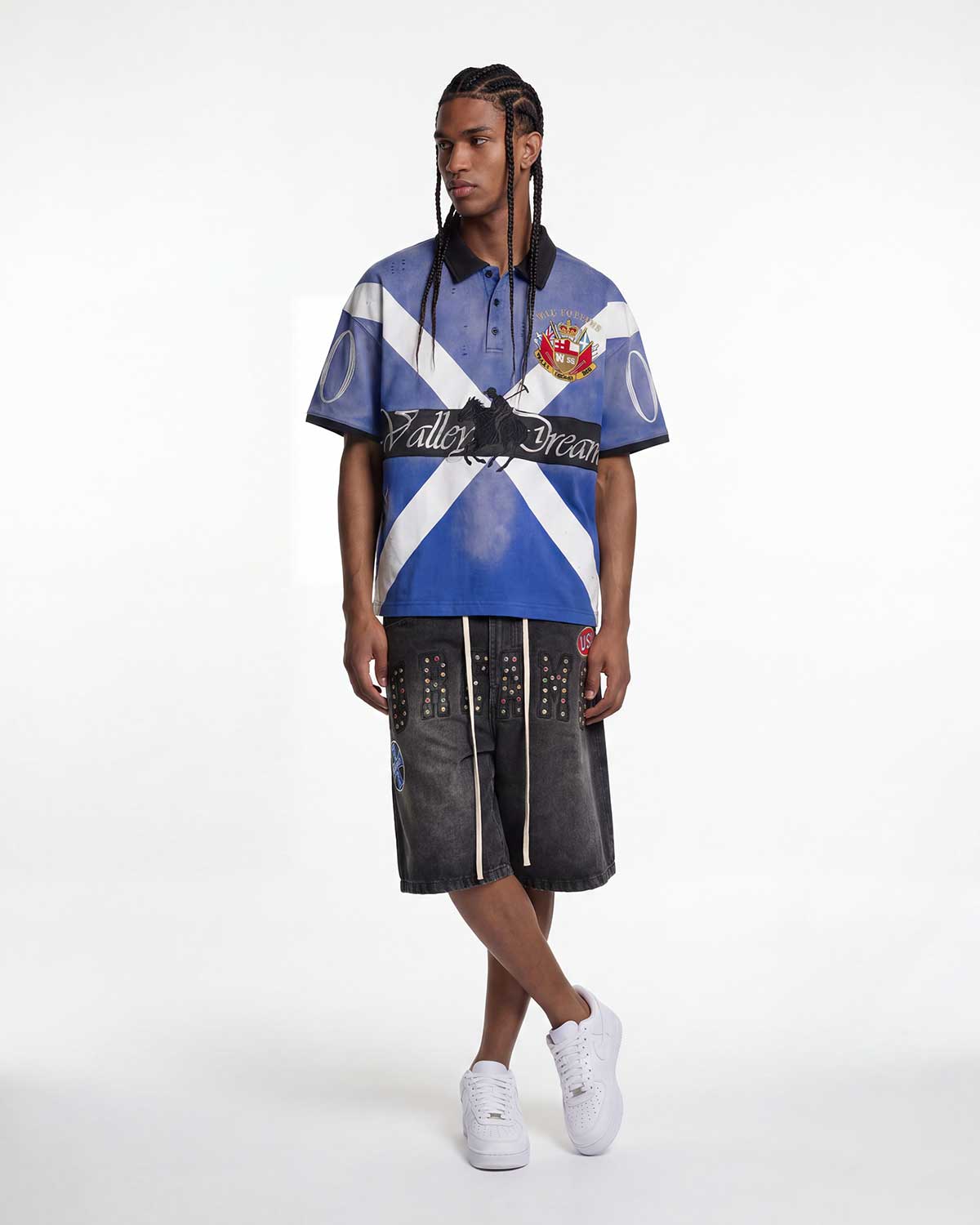 Model wearing Vale Forever Legacy Short Sleeve Polo blue with studded pants, full front view