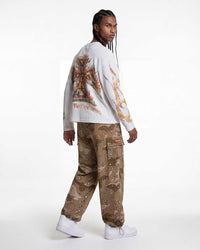 A model shown from the back wearing a white long-sleeve sweatshirt with a large gold and brown graphic print on the back, paired with brown camouflage cargo pants and white sneakers, against a plain white studio background.