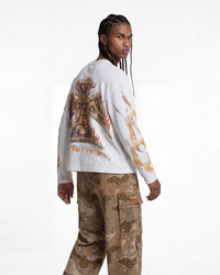 A model shown from the back wearing a white long-sleeve shirt with a large orange, gold, and brown graphic print on the back, paired with brown cargo pants.