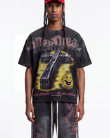 A model wearing a black acid-washed Grunt Style t-shirt with a large yellow and black graphic print, paired with matching acid-washed pants and a red cap, against a plain white background.