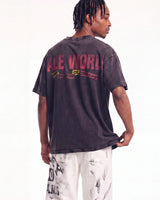 A man shown from the back wearing a faded black graphic t-shirt with 'ALL WORLD OF DISCIPLINE' printed in red and yellow on the back, paired with white distressed pants, against a plain white background.